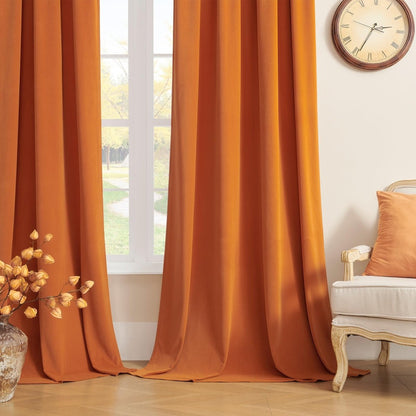 Burnt orange velvet blackout curtains, luxurious and super soft, styled by a window with a cream armchair.