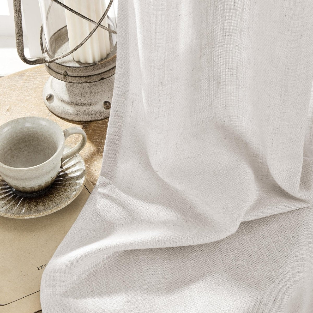 Joydeco Blanc De Blanc linen curtains close up showing natural texture and drape next to a rustic lantern and coffee cup.