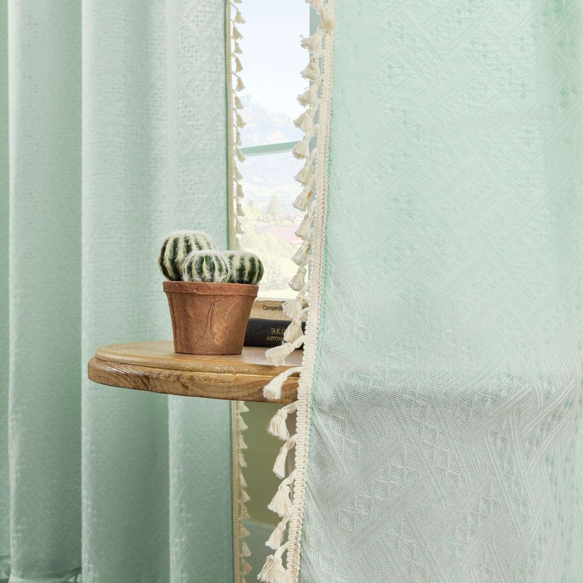 Mint green boho linen sheer curtains with geometric embroidery and cream tassel trim, filtering light.