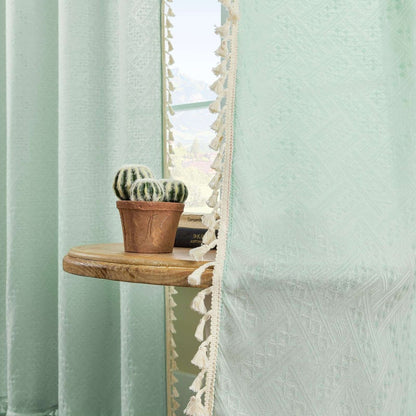 Mint green boho linen sheer curtains with geometric embroidery and cream tassel trim, filtering light.
