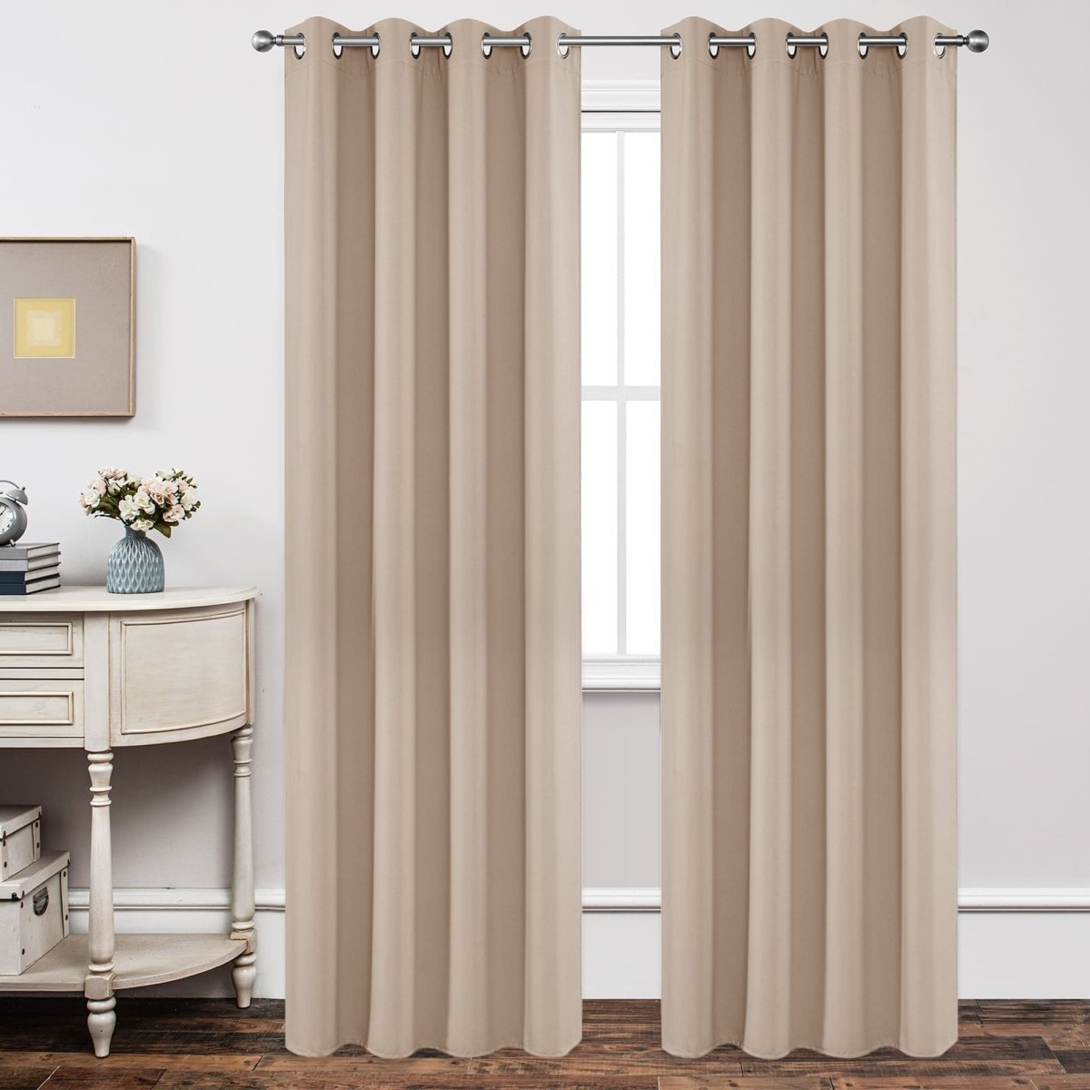 Light beige blackout curtains with grommets hang on a silver rod, showcasing smooth fabric texture on a bedroom window.