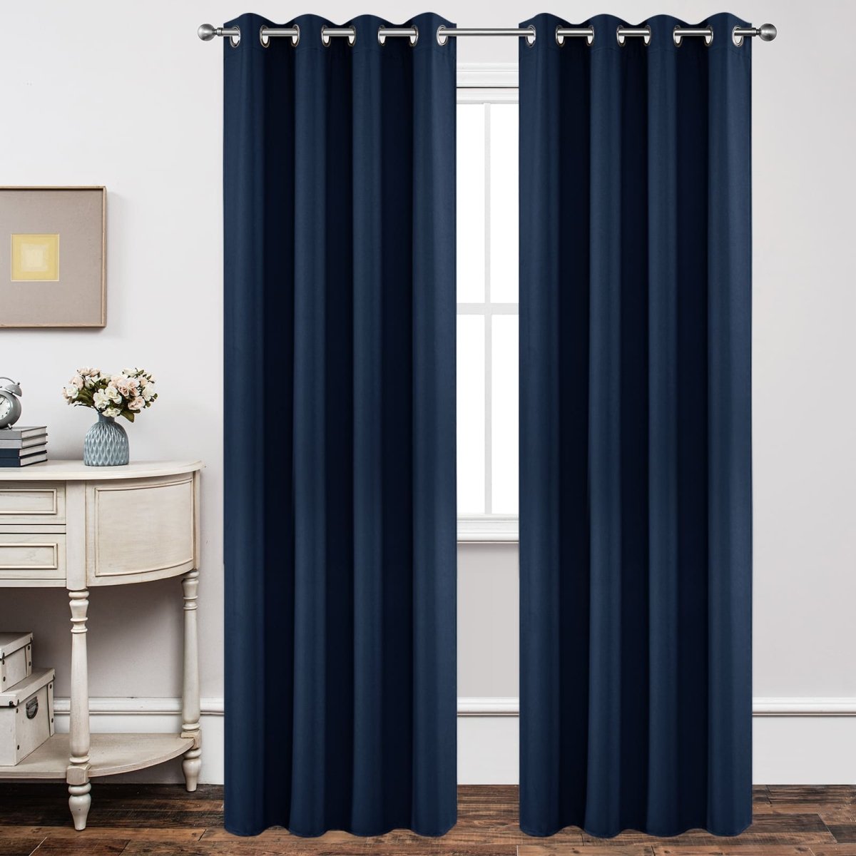 Two navy blue blackout curtain panels with silver grommets in a bedroom setting, offering light blocking and privacy.