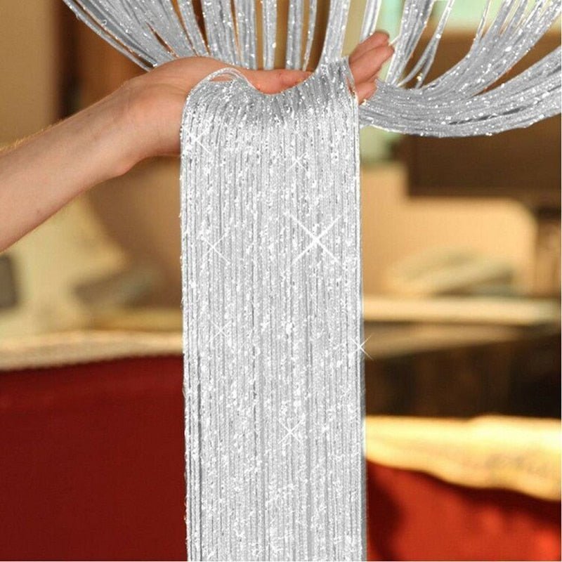 Hand holding shimmering silver glitter fringe strings, sample product showcase.